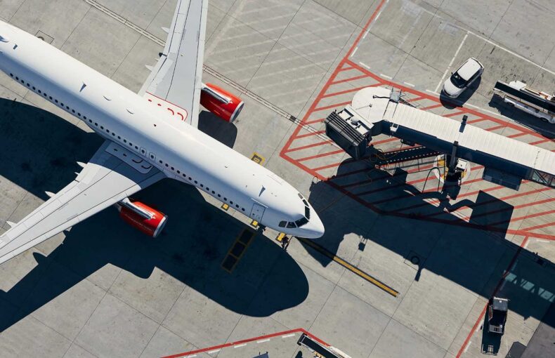 Aerial view of plane. Airplane in front of the passenger boarding bridge from airport terminal.